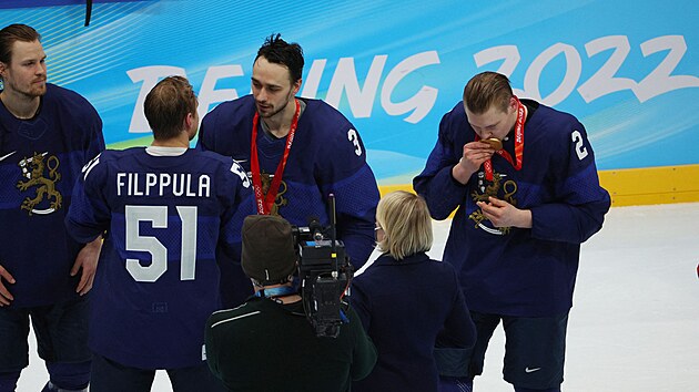 Finský hokejový obránce Ville Pokka (2) líbá zlatou olympijskou medaili. Vedle nìj mezitím spoluhráèi z obrany Niklasi Frimanovi (3) gratuluje kapitán Valtteri Filppula (51). Vlevo èeká další bek Mikko Lehtonen.
