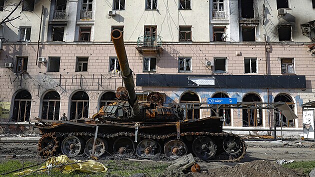 Znièený tank a poškozený bytový dùm z tìžkých bojù jsou vidìt v oblasti kontrolované separatistickými silami podporovanými Ruskem v Mariupolu. (26. dubna 2022)