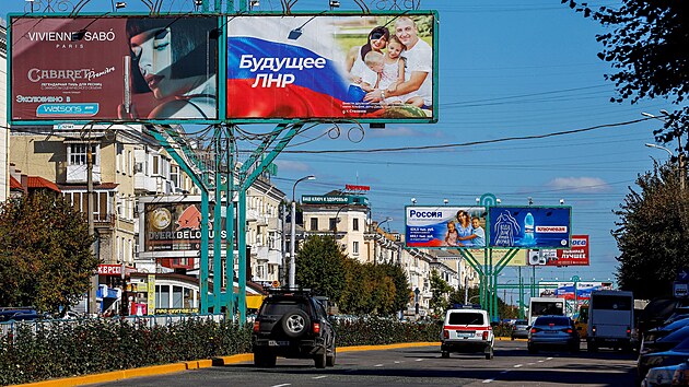 Auto projíždìjící pod billboardy s proruskými slogany v Luhansku na Ukrajinì. (20. záøí 2022)