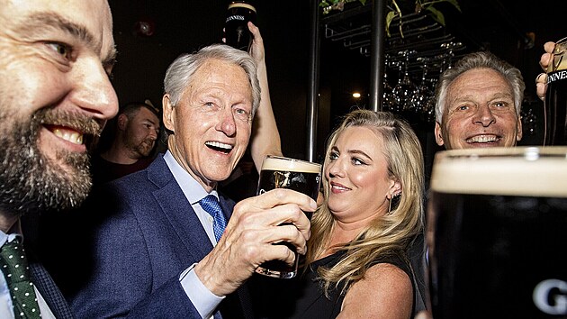 Bill Clinton a Rachael Eastwoodová, manželka opodál stojícího lídra severoirské Sociálnì demokratické a labouristické strany (SDLP) Columa Eastwooda, v hospodì v severoirském Londonderry (18. dubna 2023)
