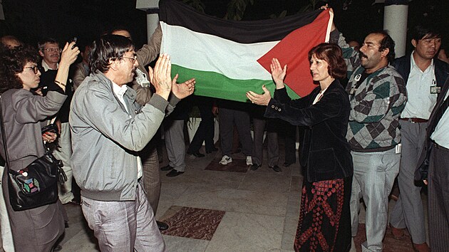 Delegáti Palestinského národního výboru tancují u palestinské vlajky. (15. listopadu 1988)