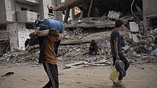 Palestinci procházejí znièenými budovami po izraelské letecké a pozemní...